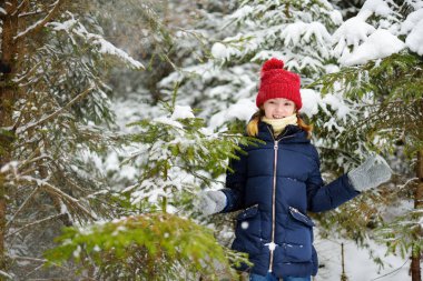 Sevimli küçük kız güzel kış ormanda eğleniyor. Bir karda oynarken mutlu bir çocuk. Çocuklar için kış aktiviteleri.