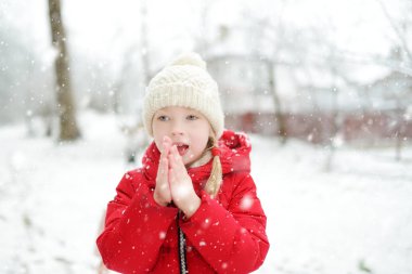 Tatlı genç kız kar yağarken güzel kış parkında eğleniyor. Karda oynayan sevimli bir çocuk. Çocuklu aileler için kış etkinlikleri.