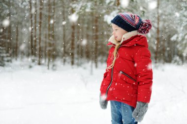 Tatlı genç kız kar yağarken güzel kış parkında eğleniyor. Karda oynayan sevimli bir çocuk. Çocuklu aileler için kış etkinlikleri.