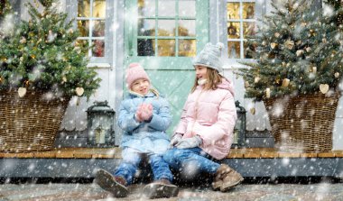 İki sevimli kız kardeş Riga, Letonya 'da geleneksel Noel fuarında birlikte iyi vakit geçiriyorlar. Çocuklar Xmas pazarında tatlı, şeker ve zencefilli ekmek yiyor..