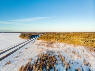Ağaçlar arasında iki şeritli bir yol olan karla kaplı güzel bir hava manzarası. Rime buzu ve ağaçları kaplayan buz kütleleri. Vilnius, Litvanya yakınlarındaki manzaralı kış manzarası.