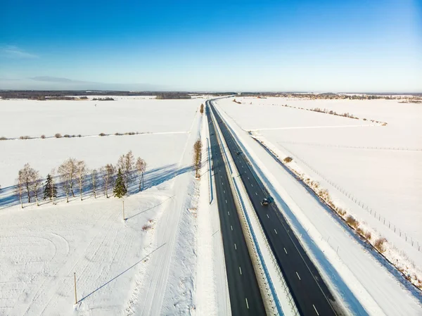 Красивый вид с воздуха на заснеженные поля с двухполосной дороги среди деревьев. Живописный зимний пейзаж под Вильнюсом . — стоковое фото