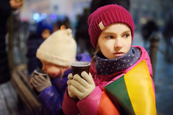 Two cute kids attending the celebration of Restoration of the State Day in Vilnius, Lithuania. Bonfires are lit on Gediminas avenue on the night on February 16.