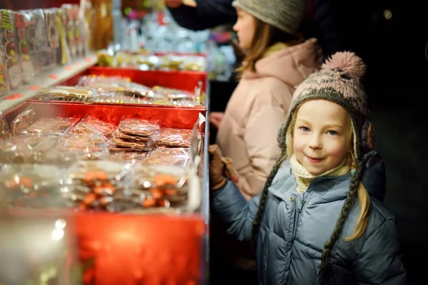 Cute young sisters choosing sweets on traditional Christmas market in Riga, Latvia. Kids buying candy and cookies on Xmas. — Stock Photo, Image
