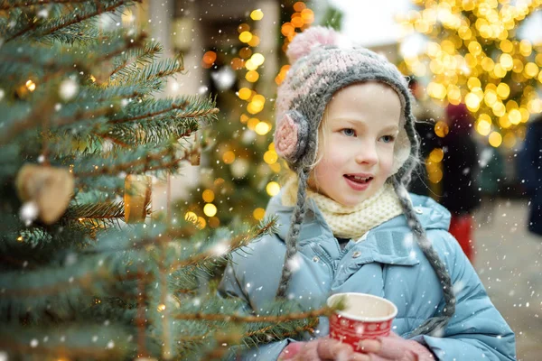 ラトビアのリガで開催される伝統的なクリスマスフェアでホットチョコレートを飲むかわいい女の子 クリスマスマーケットでお菓子やキャンディー ジンジャーブレッドを楽しむ子供たち 家族や子供と冬の時間 — ストック写真