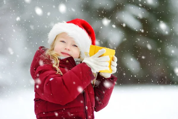 Αξιολάτρευτο Κοριτσάκι Που Φοράει Καπέλο Βασίλη Κρατώντας Χριστουγεννιάτικο Δώρο Την — Φωτογραφία Αρχείου