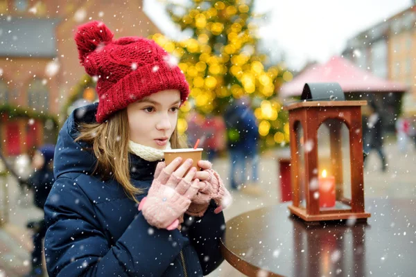 ラトビアのリガで開催される伝統的なクリスマスフェアでホットチョコレートを飲むかわいい女の子 クリスマスマーケットでお菓子やキャンディー ジンジャーブレッドを楽しむ子供たち 家族や子供と冬の時間 — ストック写真