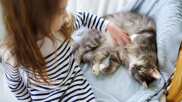 Schattig klein meisje streelde haar huisdier kat thuis — Stockfoto