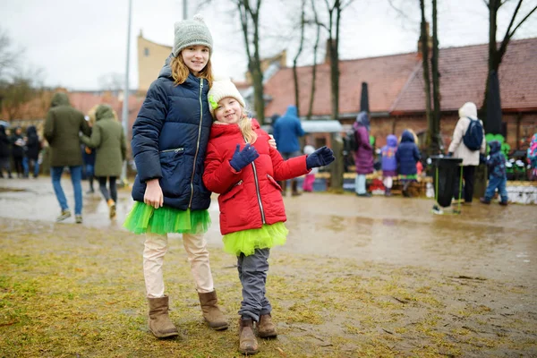 Two cute little girls wearing green skirts and accessories celebrating St. Patrick's day in Vilnius. — Stock Photo, Image
