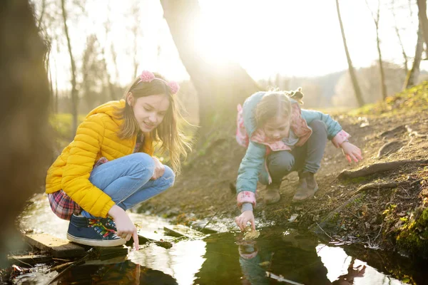 Twee schattige zusjes die plezier hebben aan een rivier op warme lentedag. Kinderen die samen spelen bij een water. — Stockfoto