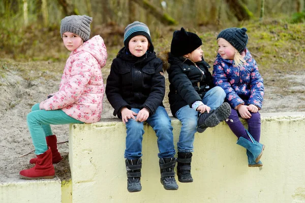 Čtyři roztomilé malé děti se spolu baví o krásném jarním dni. Vtipné děti visí spolu venku. — Stock fotografie