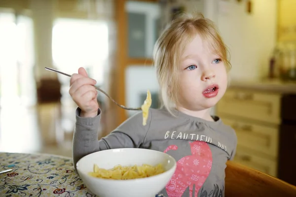 Cute funny little girl eating pasta noodles at home. — Stock Photo, Image