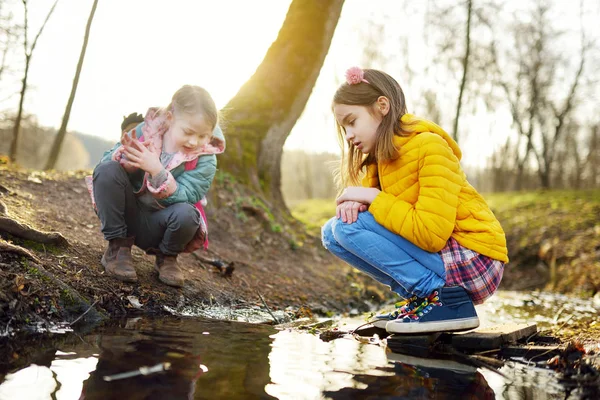 Deux jolies jeunes sœurs qui s'amusent près d'une rivière le jour du printemps chaud. Enfants jouant ensemble près d'une eau . — Photo