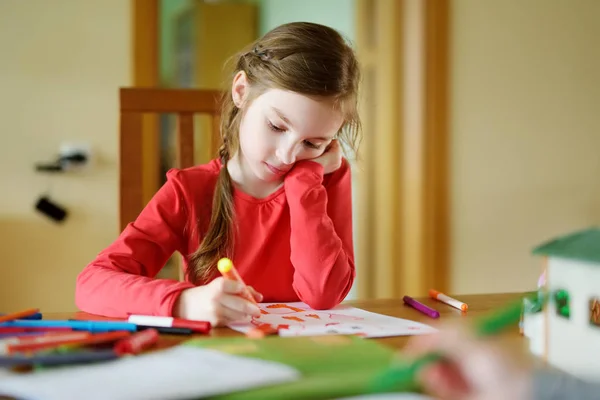 Kreşte renkli kalemlerle resim yapan sevimli küçük bir kız. Yaratıcı çocuk evde resim yapıyor.. — Stok fotoğraf