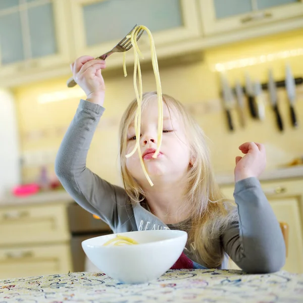 Söt rolig liten flicka äter spaghetti hemma — Stockfoto