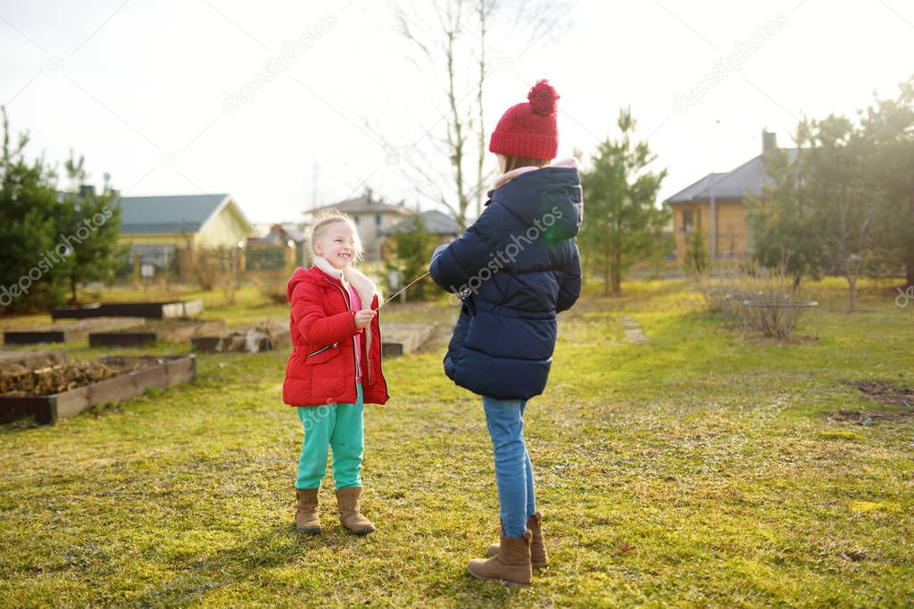 Two young sisters having fun together on beautiful spring day. Active family leisure with kids. Family fun outdoors.