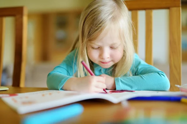 Симпатичная девушка рисует красочными карандашами в детском саду. Творческая детская живопись в школе. Девочка делает домашнее задание дома . — стоковое фото