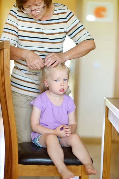 Grandmother braiding her little granddaughters hair in the morning. — Stock Photo, Image