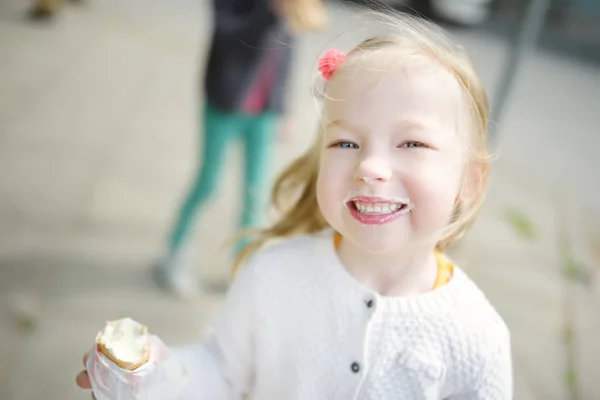 Cute girl eating tasty fresh ice cream outdoors on warm sunny summer day. Children eating sweets. — Stock Photo, Image