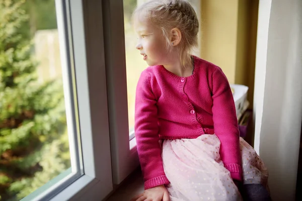 Schattig klein meisje op zoek door het raam — Stockfoto