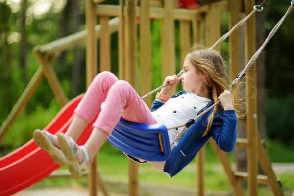 Schattig meisje die plezier heeft op een speeltuin in de zomer. Sportactiviteiten voor kinderen. — Stockfoto