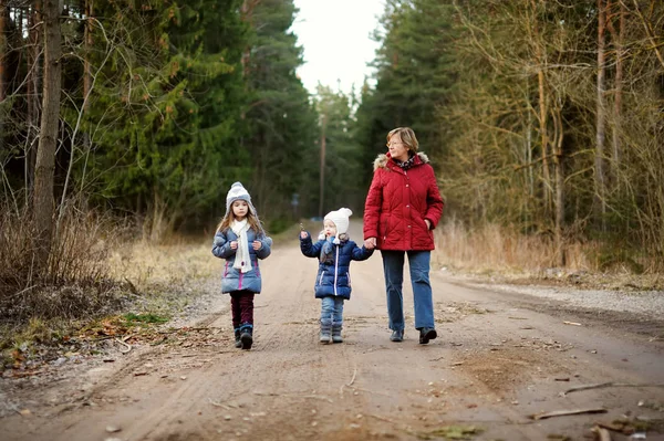 美しい春の日に祖母と一緒に森の中をハイキングする2人のかわいい妹。自然を探検する子供たち. — ストック写真