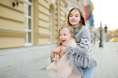 İki tatlı genç kız kardeş güzel bir bahar gününde şehirde birlikte eğleniyorlar. Çocuklarla aktif aile eğlencesi. Aile eğlencesi..
