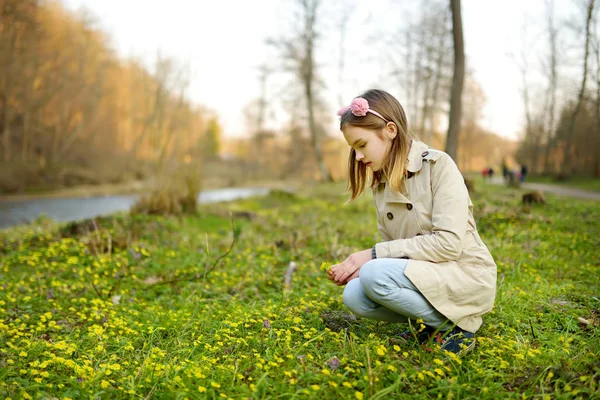 Rozkošná mladá dívka sbírá první květy jara v lese na krásném slunném jarním dni. Roztomilé dítě baví venku. — Stock fotografie