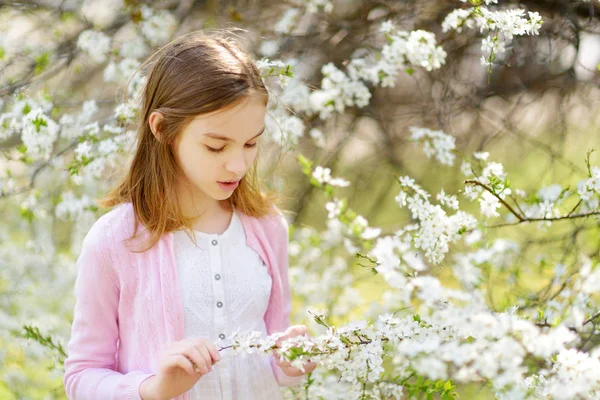 美しい春の日に桜の庭を楽しむ愛らしい少女 桜の枝にイースターエッグをぶら下げている子供 屋外でイースターを祝う子供 — ストック写真