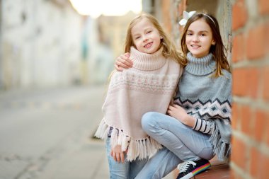 İki tatlı genç kız kardeş güzel bir bahar gününde şehirde birlikte eğleniyorlar. Çocuklarla aktif aile eğlencesi. Aile eğlencesi..