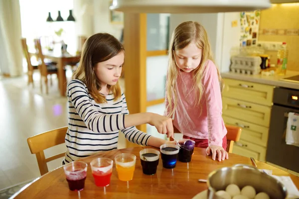 自宅のイースターエッグを染色 つかわいい若い姉妹 子供たちはイースター ハントのカラフルな卵を塗るします 子供たちはイースターのお祝いの準備を 家族の伝統 — ストック写真