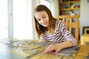 Evde yapboz oynayan tatlı bir genç kız. Çocuk oturma odasındaki yapboz parçalarını birleştiriyor. Çocuk yapboz yapıyor. Eğlenceli aile eğlencesi. Çocuklar için evde kal..