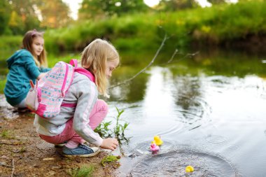 Renkli lastik ördeklerin olduğu bir nehrin kenarında oynayan iki genç kız kardeş. Çocuklar sıcak yaz gününde suyla eğleniyorlar. Aktif aile eğlencesi..