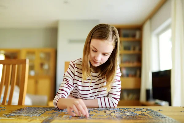 かわいい若い女の子が家でパズルをしている リビングルームのテーブルにジグソーパズルのピースを接続する子 ジグソーパズルを組み立てる子供 楽しい家族のレジャー 子供のための家の活動に滞在する — ストック写真