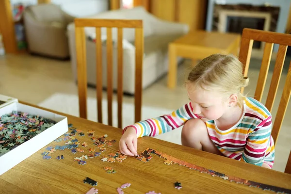 귀여운 집에서 놀이를 있습니다 아이들 테이블에 조각들을 합니다 퍼즐맞추기를 중이야 — 스톡 사진