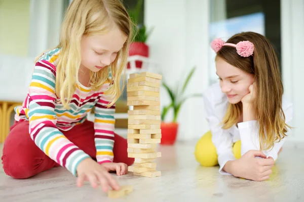家で木のブロックタワーゲームをしている2人のかわいい姉妹 子供たちは身体的および精神的なスキルを練習します 家族のレジャーのための楽しいボードゲーム 子供のための家の活動に滞在する — ストック写真
