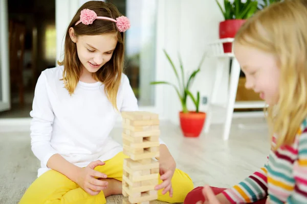 两个可爱的姐姐在家里玩木块塔游戏 孩子们在练习他们的身体和精神技能 家庭休闲的棋盘游戏 为孩子们在家里活动 — 图库照片