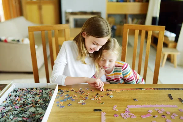 귀여운 소녀들 집에서 놀이를 있습니다 아이들 테이블에 조각들을 합니다 퍼즐맞추기를 — 스톡 사진