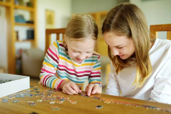 かわいい若い女の子が家でパズルをしている リビングルームのテーブルにジグソーパズルのピースを接続する子供たち ジグソーパズルを組み立てる子供たち 楽しい家族のレジャー 子供のための家の活動に滞在する — ストック写真
