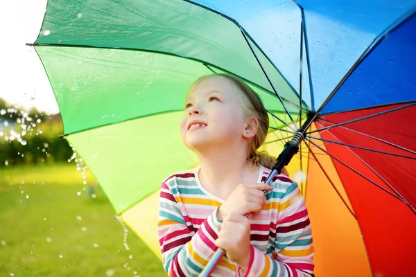 多雨的夏日 可爱的小女孩拿着彩色彩虹伞 孩子们在室外暖雨中散步 为儿童举办的户外暑期活动 — 图库照片