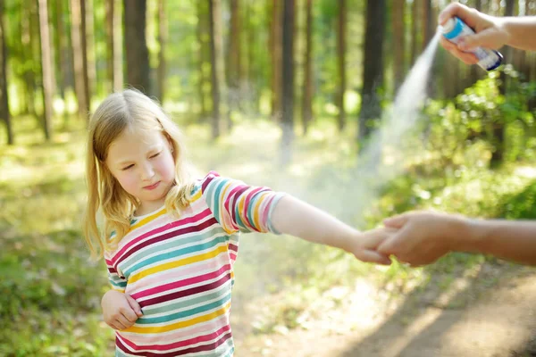 妈妈在森林徒步旅行美丽的夏日前对女儿施用驱虫药 在夏天保护孩子们不咬昆虫 用喷雾器与孩子的积极闲暇 — 图库照片
