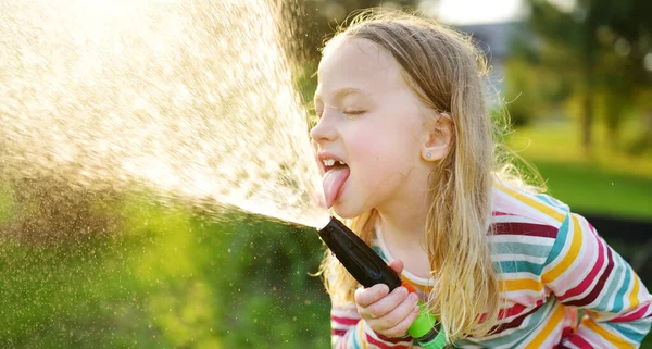 可爱的小女孩在温暖的夏天玩花园软管 孩子们在炎热的天气里喝水很开心 为儿童举办的户外暑期活动 — 图库照片