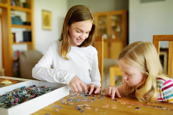 귀여운 소녀들 집에서 놀이를 있습니다 아이들 테이블에 조각들을 합니다 퍼즐맞추기를 — 스톡 사진
