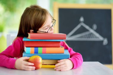 Akıllı liseli kız masasında bir yığın kitapla ders çalışıyor. Genç kız ödevini yapıyor. Çocuklar için eğitim ve uzak mesafe eğitimi. Karantina sırasında evde eğitim. Evde kalıp eğlenin..