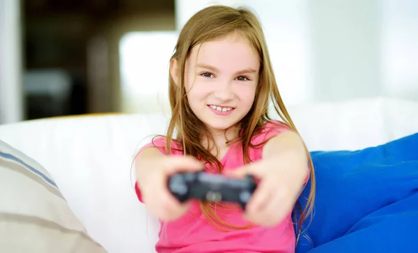 Funny little girl playing with game console at home. Child having fun in front of the TV. Kid playing video games. Family leisure. Stay at home entertainment.
