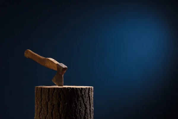The axe stuck in the wooden stump on a dark background. — Stock Photo, Image