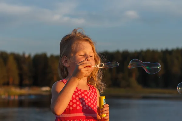 Liten flicka spelar med såpbubblor utomhus. — Stockfoto