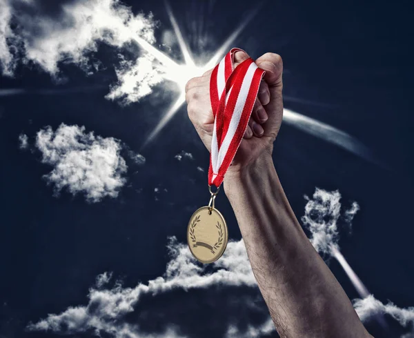 Hand met een medaille op de hemelachtergrond — Stockfoto