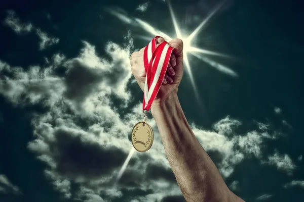 Hand met een medaille op de hemelachtergrond — Stockfoto