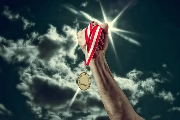 Hand mit Medaille auf Himmelshintergrund — Stockfoto